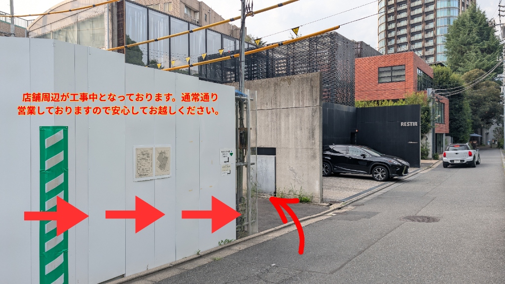 【ステップ1】仮囲いの横を奥へ：通り沿いの仮囲い横を奥へ進む矢印案内