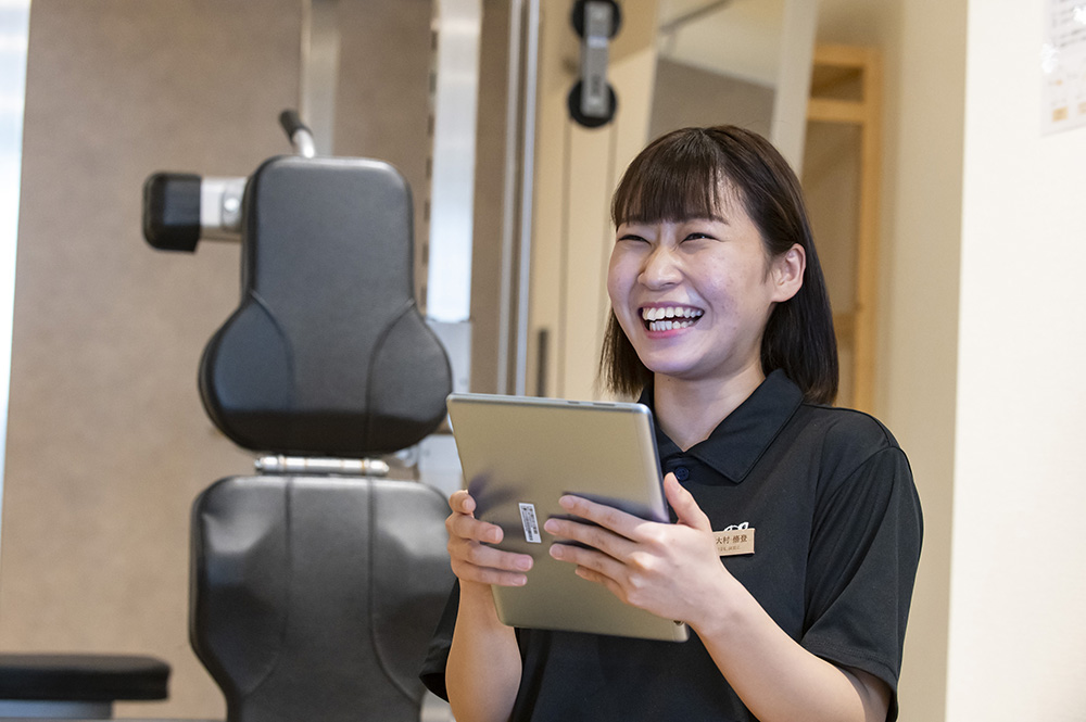 タブレットを持った笑顔の中川トレーナー