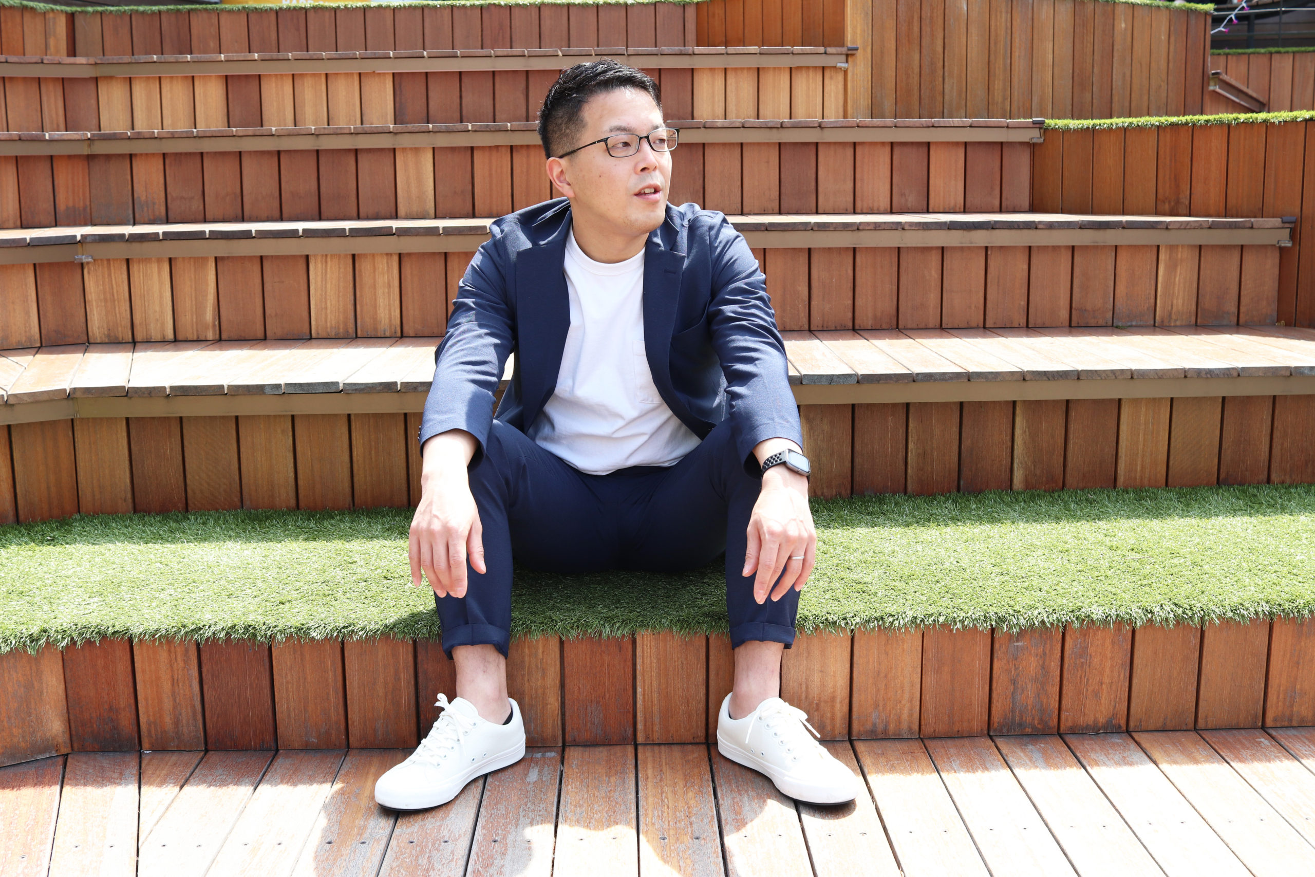 広げた足に手を置いて座る松原さん