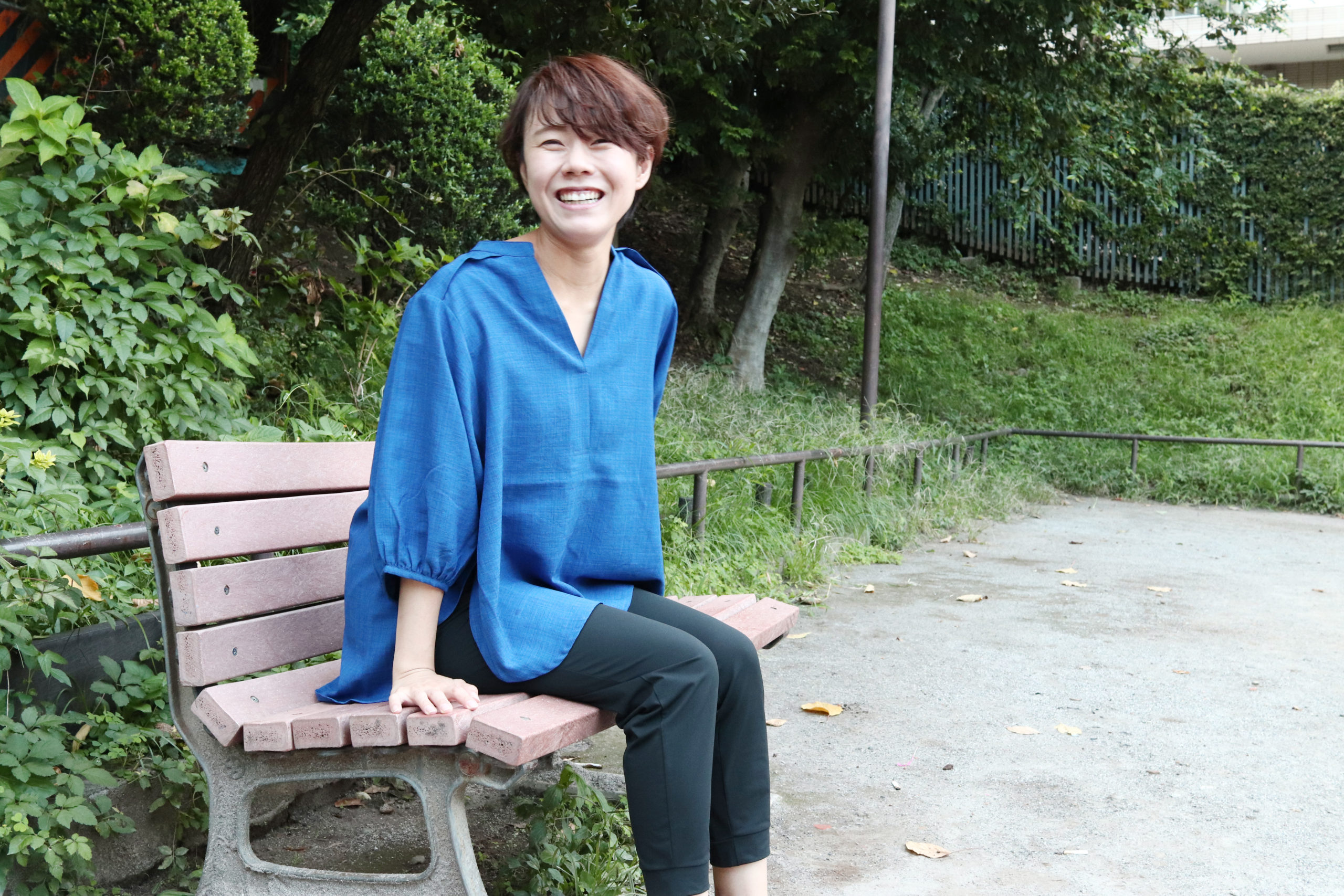 ベンチに座って笑顔を向ける山田トレーナー