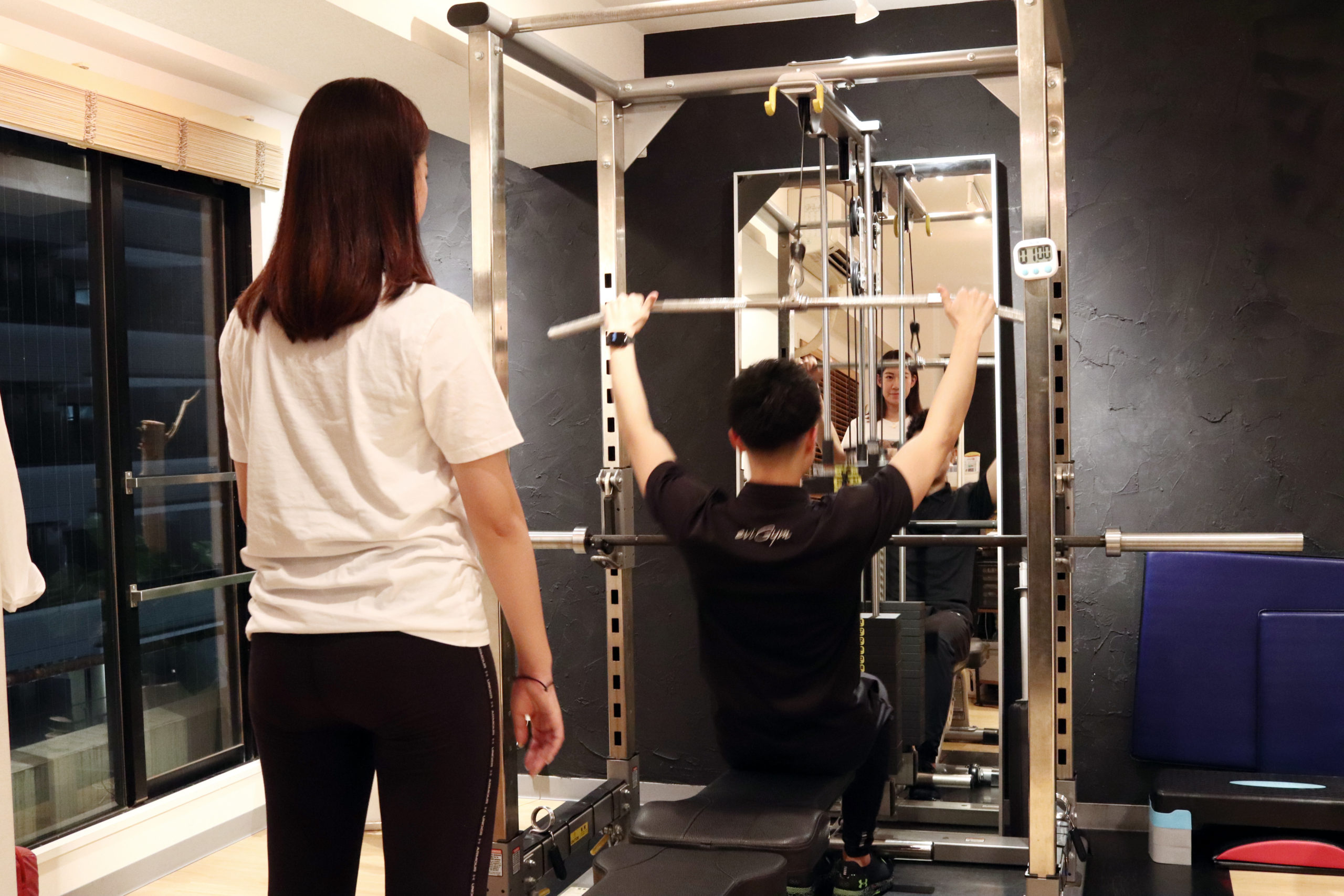 パワーラックに座るトレーナーを見ているお客様