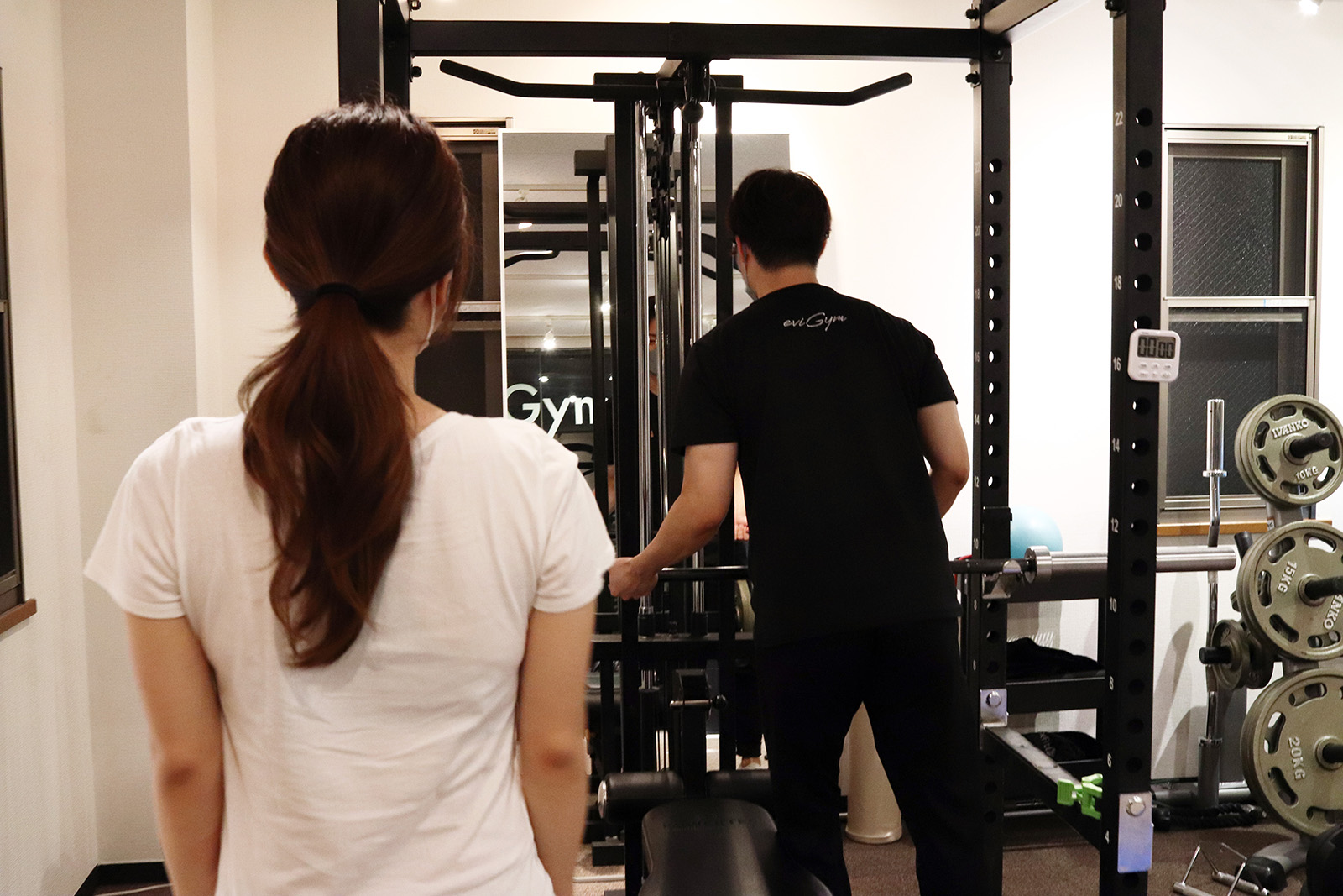 パワーラックの前に立つお客様とトレーナー