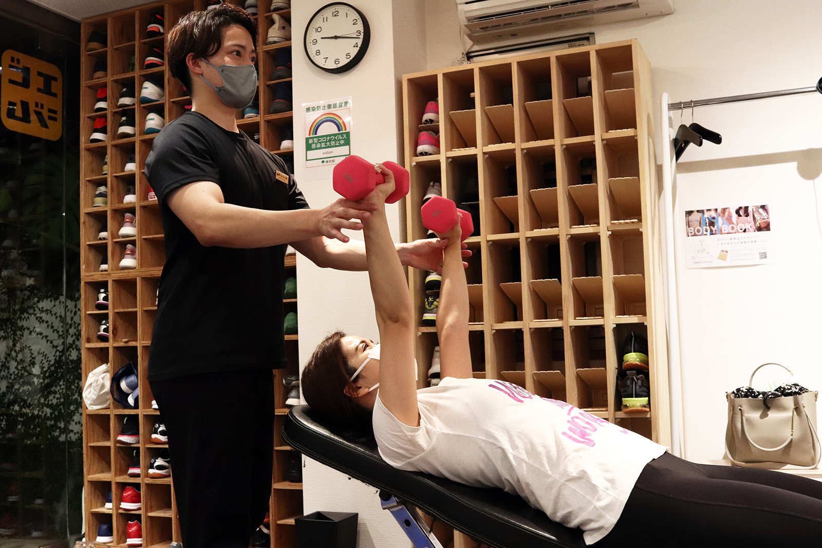 仰向けでダンベルを持ち上げるお客様とトレーナー