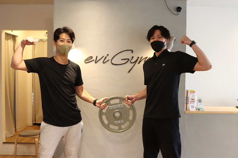 腕を上げてポーズをとるお客様とトレーナー