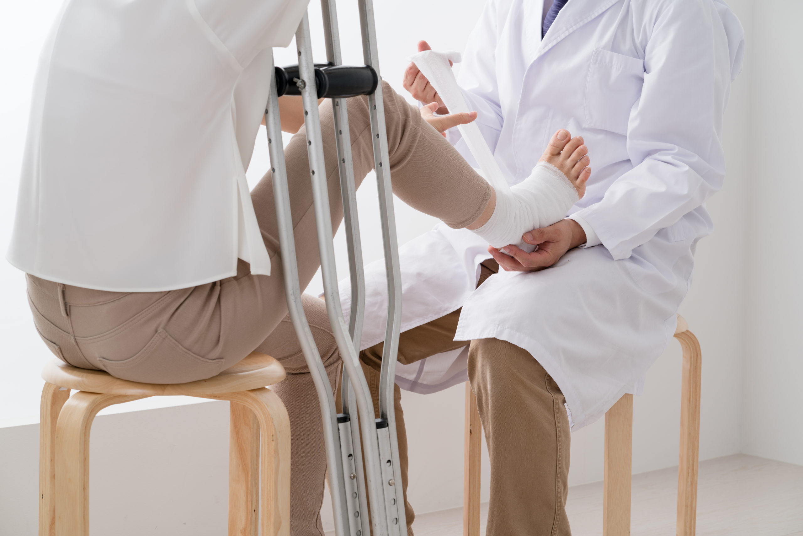 診察を受ける女性、怪我、足、松葉杖